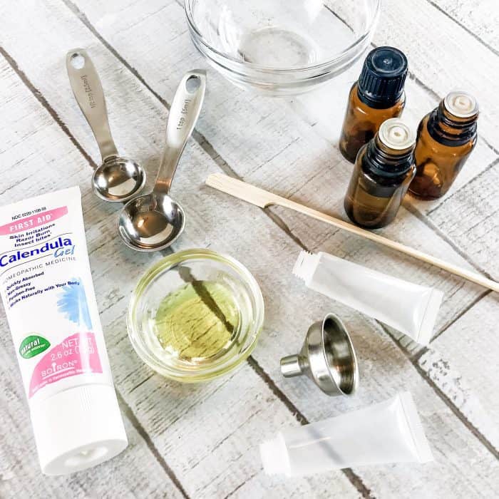 supplies to make DIY acne gel- 3 essential oil bottles, oil, calendula gel, measuring spoons, small funnel and small squeezable tubes