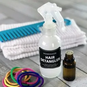 homemade hair detangler spray, wide tooth comb, and essential oil bottle