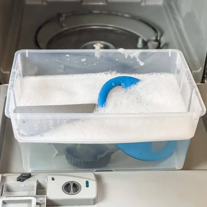 dishwasher cleaning spray arms are being soak in tub of hot soapy water