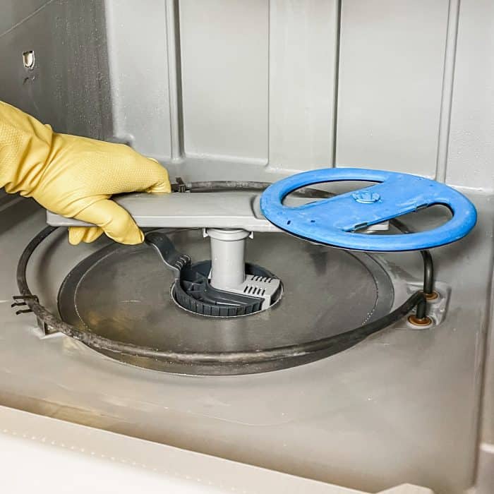 putting dishwasher filter and spray arm back in place after being cleaned