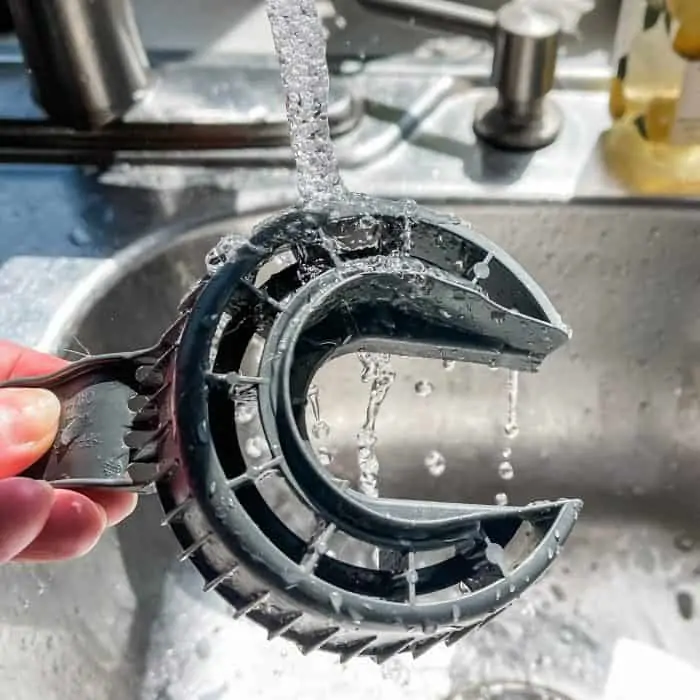 rinsing dishwasher filter under hot water