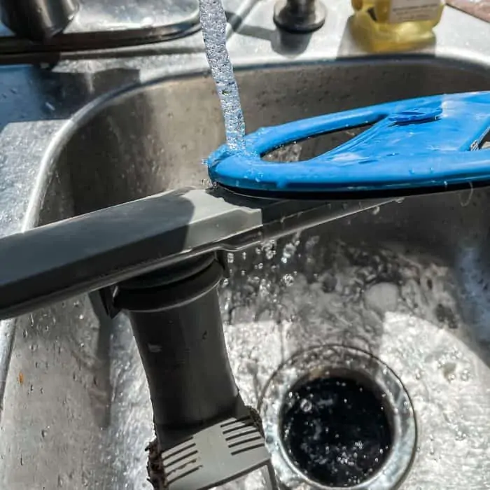 rinsing dishwasher spray arm under hot water