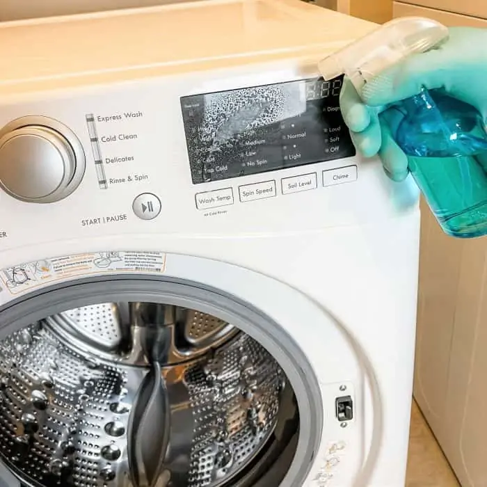 spraying homemade natural cleaner on washing machine