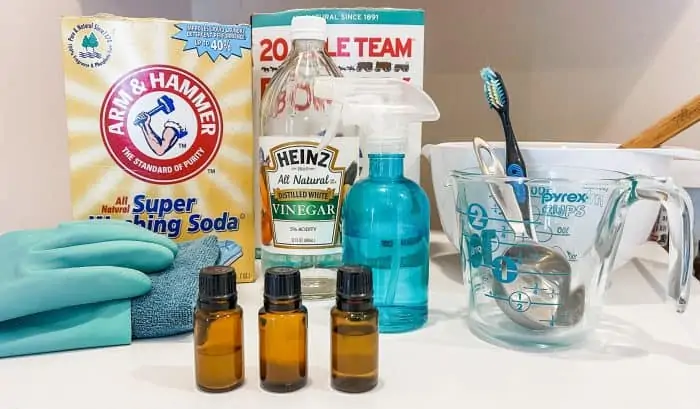 supplies used to deep clean washing machine with essential oil (washing soda, borax, vinegar, water, spray bottle, toothbrush)