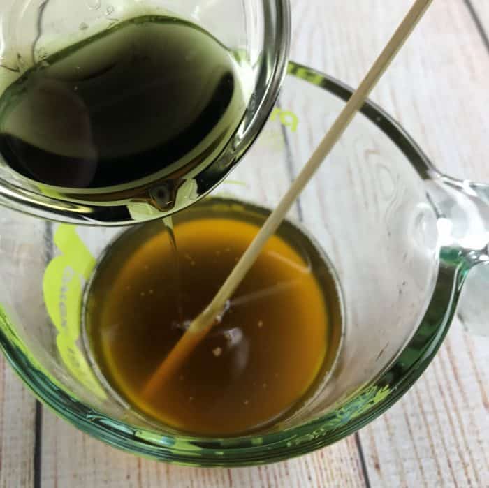 tamanu oil being added to melted beeswax and coconut oil
