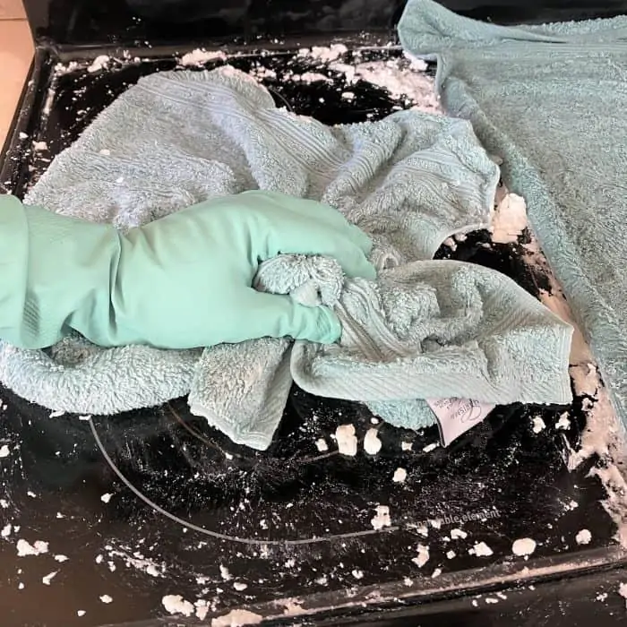 using towel to scrub cooktop with baking soda mixture