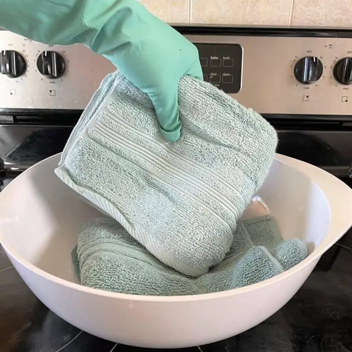 submerging towels in hot water and dish soap mixture