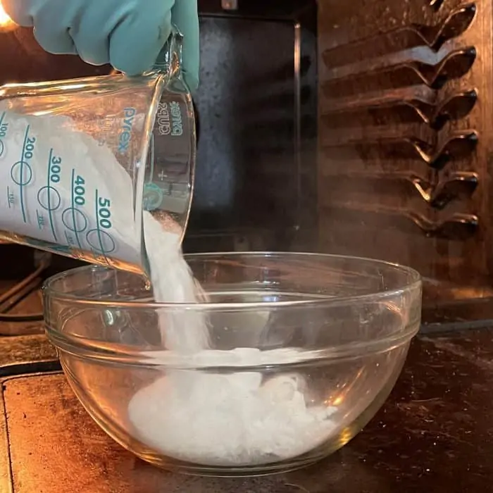 adding baking soda to bowl to make homemade oven cleaner