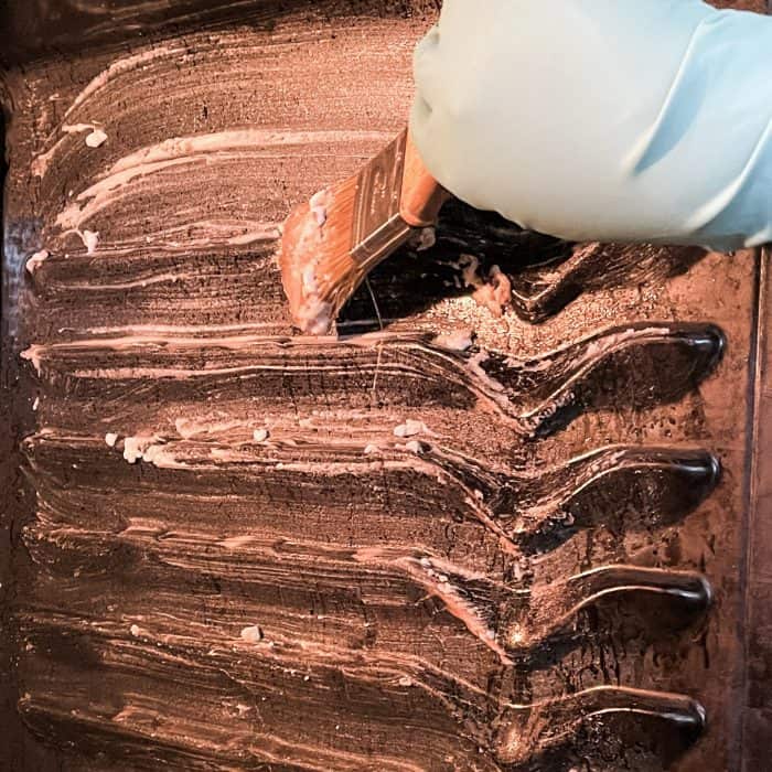 brushing cleaning paste onto oven walls