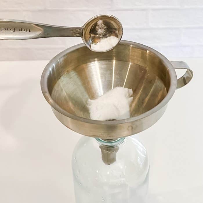 using funnel to add baking soda to glass spray bottle