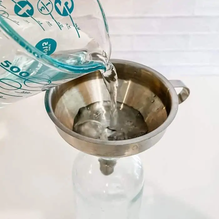 using funnel to add distilled water to glass spray bottle