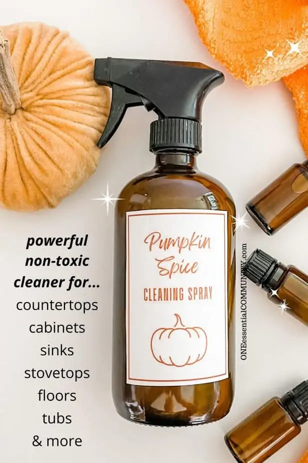 Pumpkin Spice Cleaning Spray by oneessentialcommunity.com -- powerful, non-toxic cleaner for countertops, cabinets, sinks, stovetops, floors, tubs, and more. shows amber glass spray bottle with free printable label, 3 essential oil bottles, orange dish towel, and velvet pumpkin