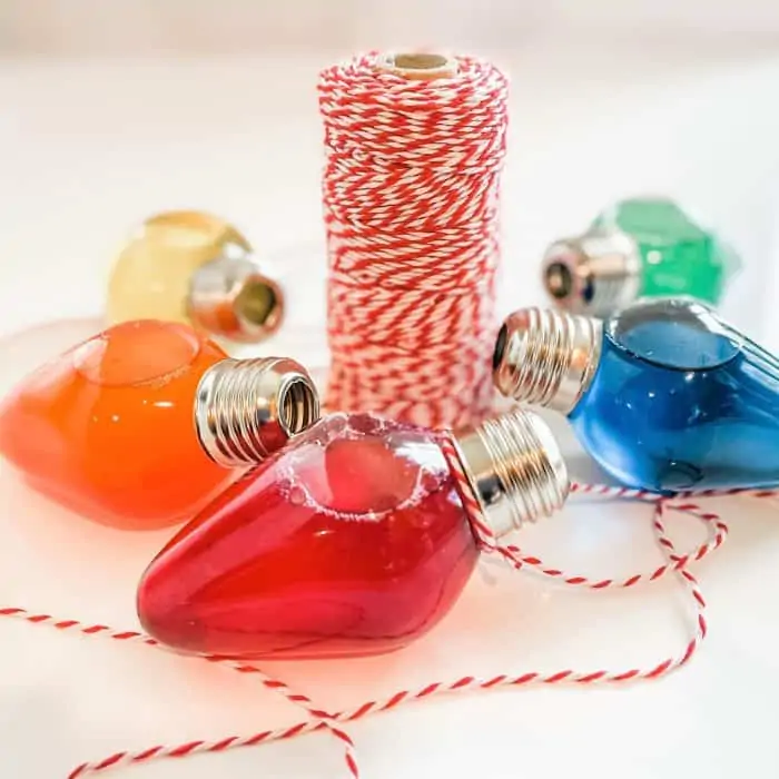 tying red & white twine around the neck of red bath oil ornament -- 4 other ornaments are in background