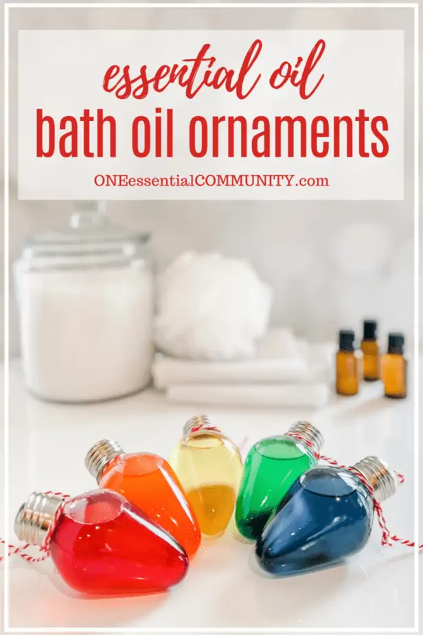 Essential oils bath oil ornaments by oneessentialcommunity.com -- red, orange, yellow, green, and blue bath oil ornaments are on table -- jar of bath salts, poof, washcloths, and essential oils are in background