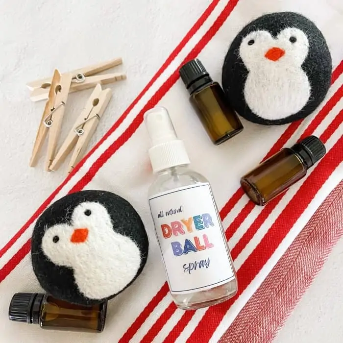 all natural dryer ball spray next to essential oil bottles, wool dryer balls, and clothes pins