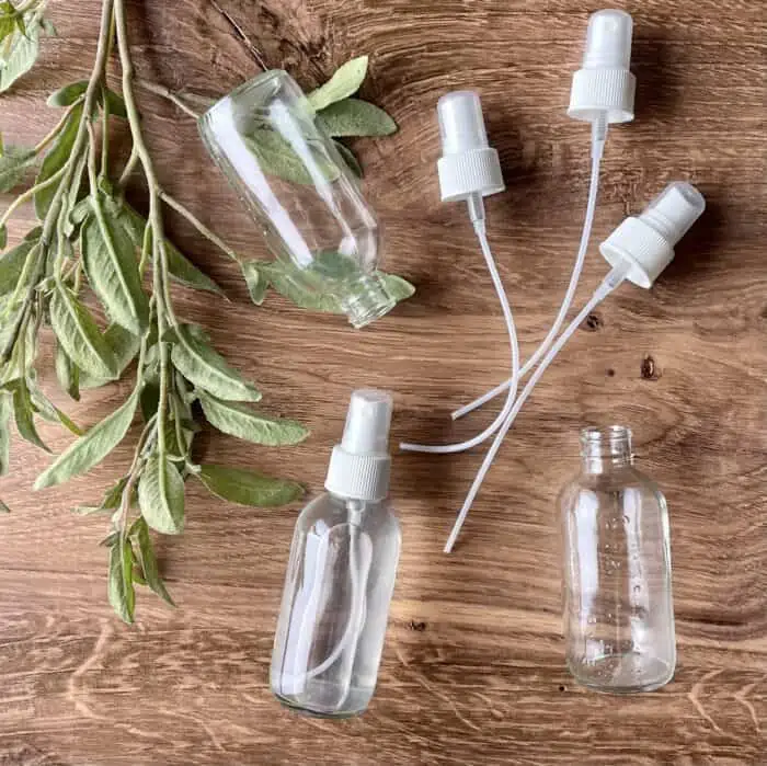 3 glass bottles and sprayers with greenery branch