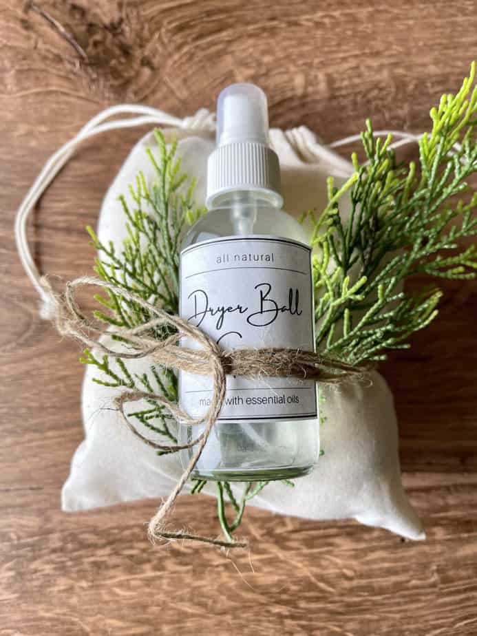 homemade dryer ball spray wrapped as gift with canvas bag containing several dryer balls and greenery sprig for decoration