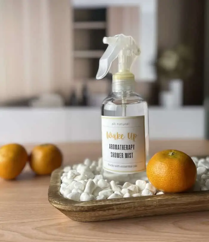 wake up Aromatherapy shower mist on wooden tray next to 3 clementines