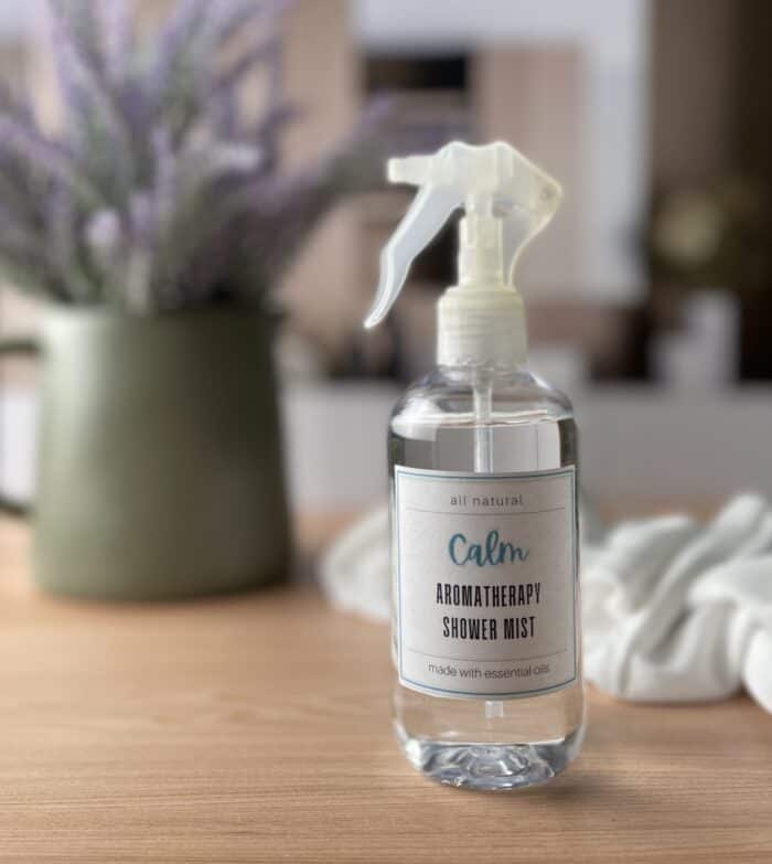 calm Aromatherapy shower mist one spa counter in front of lavender floral arrangement