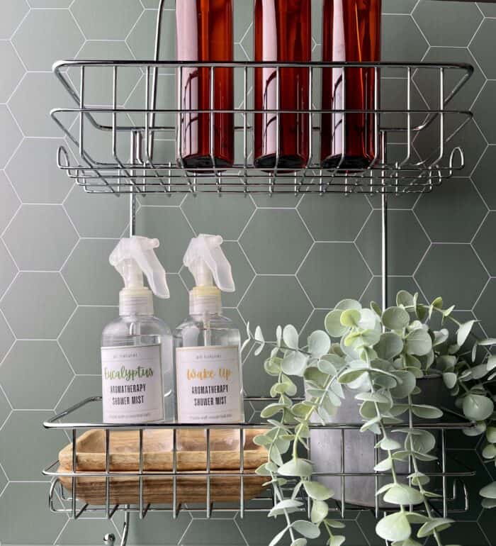 2 aromatherapy shower mist spray bottles and a plant on a shower organizer