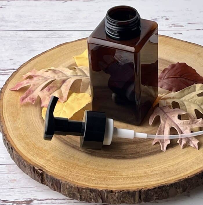 foaming soap bottle and fall leaves on wood