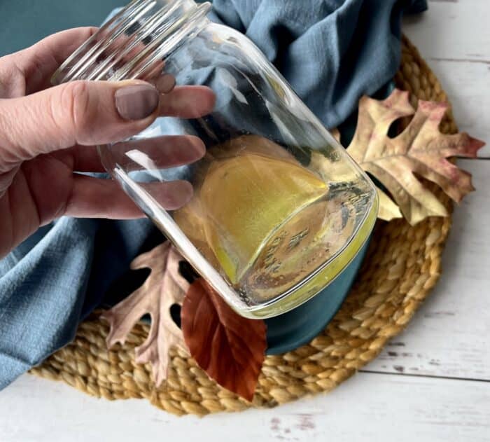 hand swirling oil and essential oils together to mix