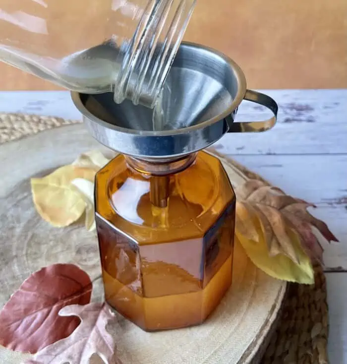 adding homemade reed diffuser liquid to amber glass vase