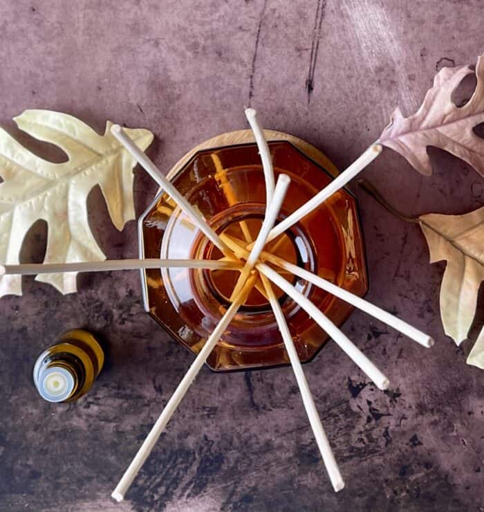 DIY reed diffuser next to essential oil bottle and a few fall leaves