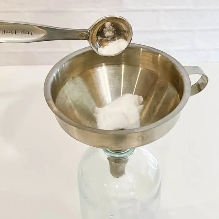 using funnel to add baking soda to glass spray bottle