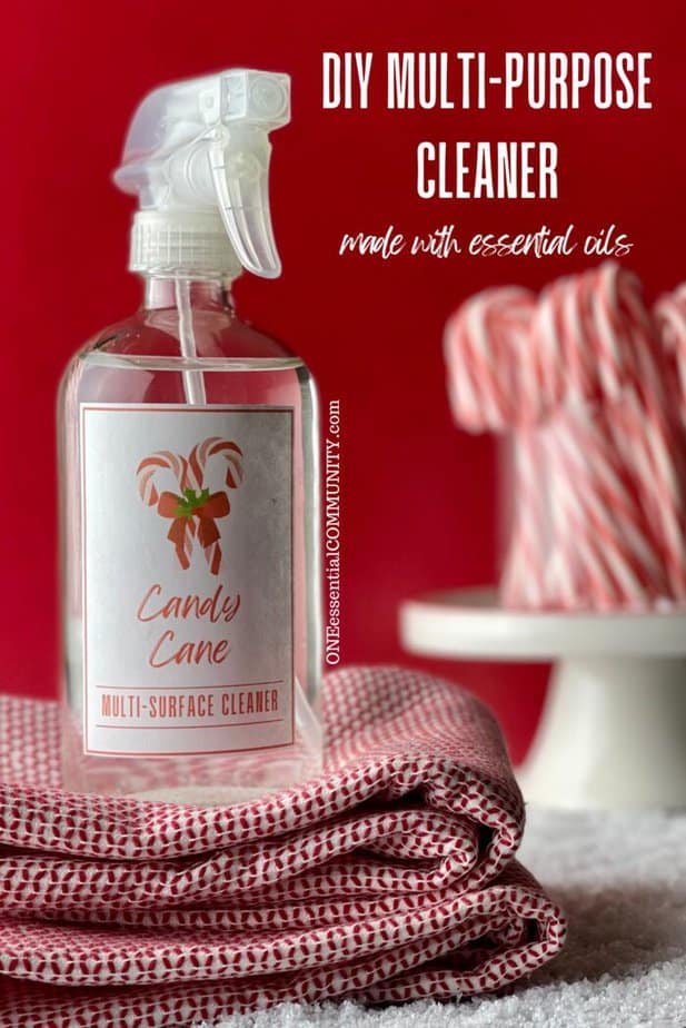 DIY multi-purpose cleaner made with essential oils by oneessentialcommunity.com -- glass spray bottle of Candy Cane multi-purpose cleaner on top of red & white dish towels... jar of candy canes on top of pedestal in background